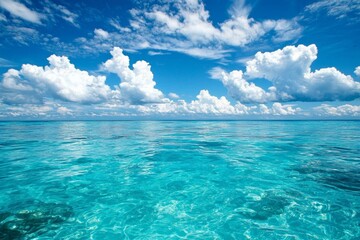 Obraz premium A serene scene of the clear blue sky and turquoise ocean, with fluffy white clouds in the background. The water is crystal clear, reflecting the vibrant colors of the sky above it. 