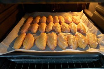 Raw chicken wings ready to roast in the open oven