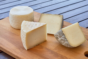 Wooden board with four wedges of artisan cheese