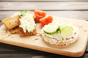 Crispbread with cream cheese and vegetables on wooden board