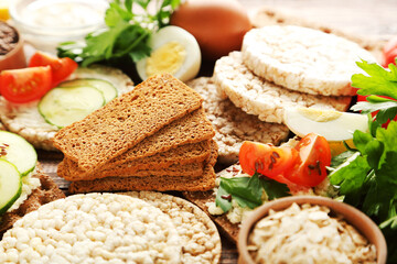 Crispbread with cream cheese and vegetables on wooden table