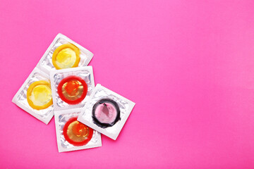Colorful condoms on pink background
