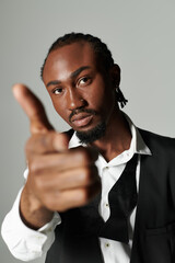 A sharply dressed young man exudes confidence while posing against a modern grey backdrop, showcasing his style.