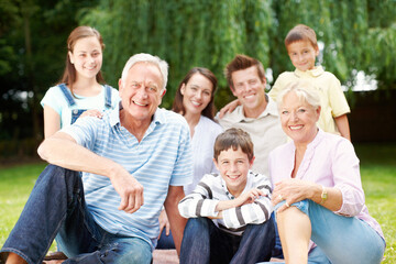 Obraz premium Happy, portrait and big family with children in nature for holiday, weekend or bonding together. Grandparents, parents and kids with smile, joy or generations for picnic or outdoor vacation at park