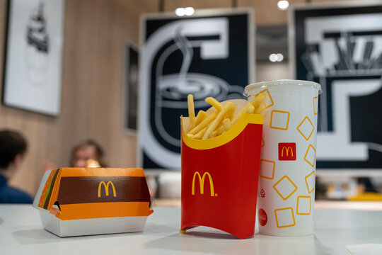 McDonald's food on the table in the restaurant interior. McDonald's logos on a French fries box, Big Mac box and soft drink cup. Minsk, Belarus - November 21, 2022