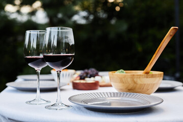 Close up background image of beautiful dining table setting outdoors with focus on two glasses with red wine copy space