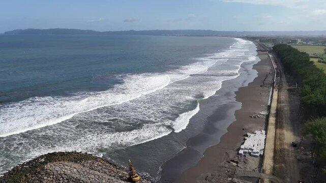Waves and black sand at Kemiren Beach Cilacap with a background of blue sea and blue sky, 4K