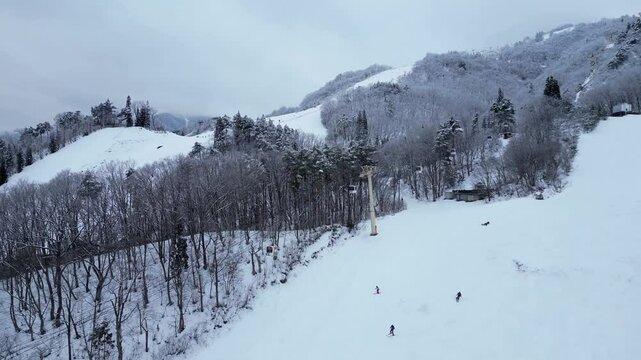 Hakuba, Japan: Aerial drone footage of the ski resort in Akuba and its gondola in the Japanese alps in Nagano prefecture on a snowy winter day. 