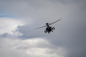 close-up of a British army Boeing Apache Attack helicopter gunship AH64E AH-64E ArmyAirCorp banking in low level overhead flight