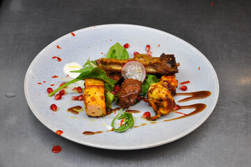 Delightful mix of grilled meats, vibrant greens, and artistic sauces. The plate features tender pieces of chicken and lamb, garnished with fresh herbs and drizzled with a balsamic reduction.