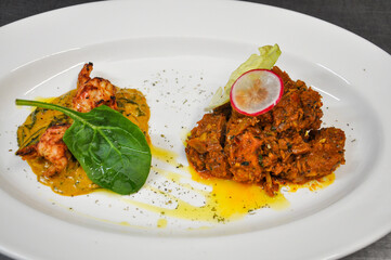 On the left, a portion of shrimp with vibrant greens, garnished with fresh spinach. On the right, a rich textured serving with juicy fish curry, 