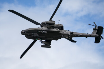 close-up of a British army Boeing Apache Attack helicopter gunship AH64E AH-64E ArmyAirCorp banking hard in low level overhead flight