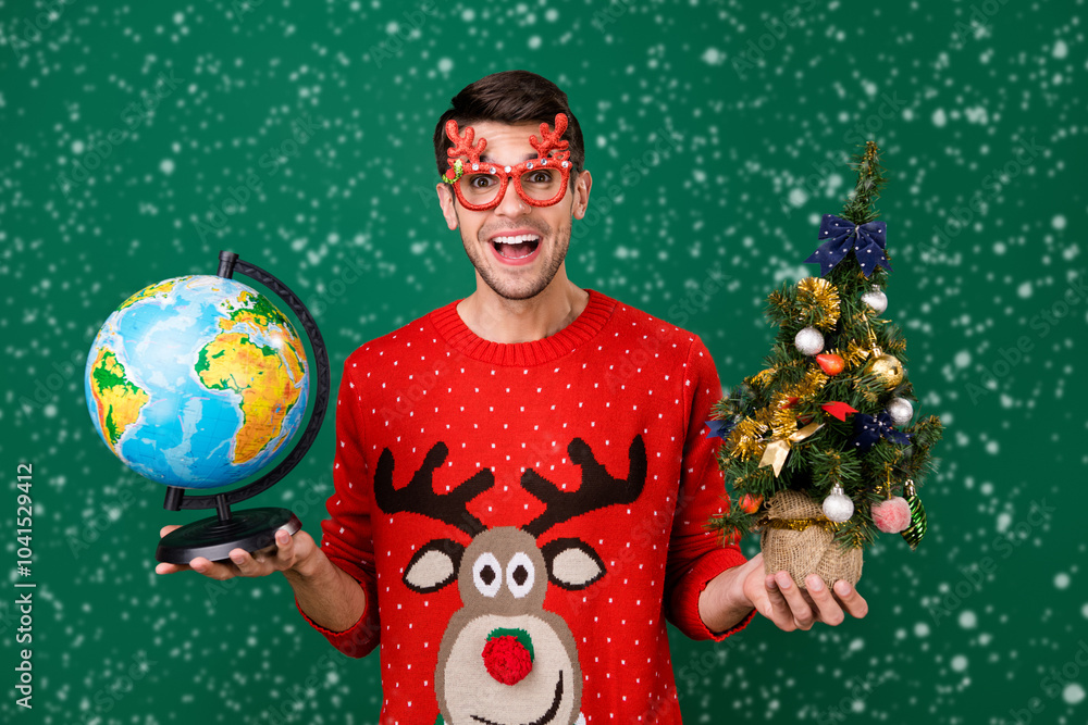 Poster portrait of attractive trendy cheerful guy holding small tree globe having fun winter isolated over 