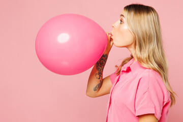 Side profile view young woman she wearing shirt celebrating birthday holiday and blowing big air...