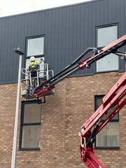 window cleaner workers using a cherry picker on a construction site