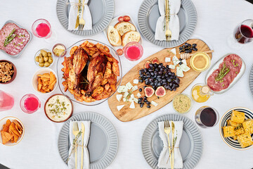 Top view background image of festive dinner table with delicious roasted chicken and snacks on crisp white cloth shot with flash