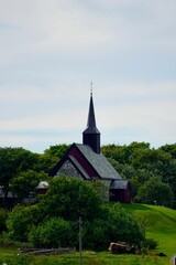 Quaint stone church with steeple surrounded by greenery.