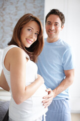 Fototapeta premium Couple, happy and pregnant with portrait, stomach and bonding in home for future motherhood support. People, smile and healthy pregnancy development for prenatal care, maternity and growth with relax