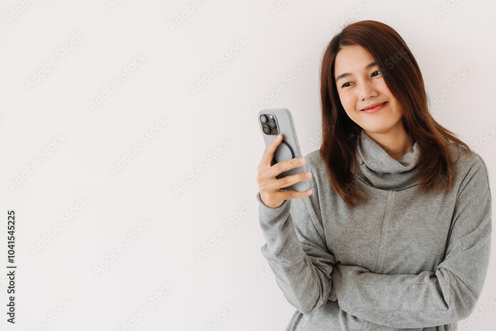 Wall mural happy asian thai woman holding and using mobile phone, wearing grey sweater in winter, standing isol