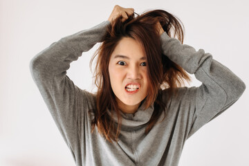 Funny angry asian Thai woman wear sweater, going crazy mad, hand gesture, isolated over white background wall.