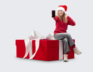 Woman with Christmas present gift box she showing the smartphone and wears Santa hat. Template for commercial sign. Store and mall Billboard top deals and sale, holiday offer or online shopping banner