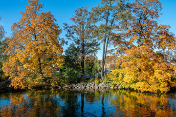 Fototapeta premium Autumn colors at Strömsholmen islet in Motala Stream during autumn in Norrköping, Sweden 