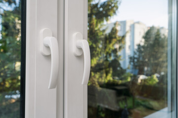 Close-up view of modern window handles in room with forest on backgrounds