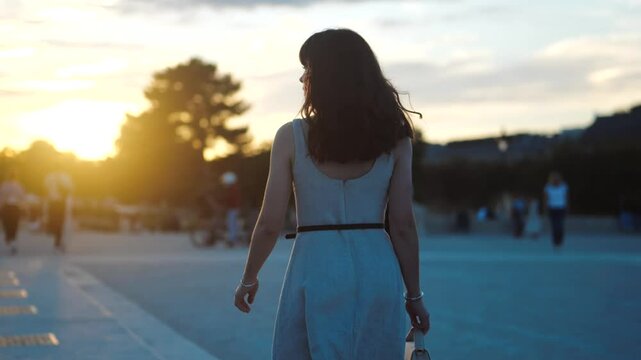 Beautiful woman walking towards the sunset in paris, from behind