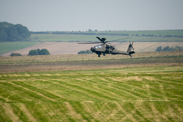 British army Boeing Apache Attack helicopter gunship AH64E AH-64E ArmyAirCorp hovering at low level over a grass meadow