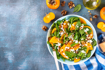 Sweet, savory delicious Persimmon autumn Salad with baby spinach leaves, cottage cheese and...