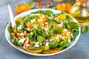 Sweet, savory delicious Persimmon autumn Salad with baby spinach leaves, cottage cheese and...