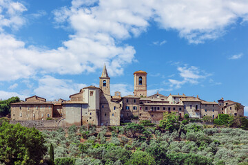 Fototapeta premium Collemancio, a historic hamlet in Cannara, Umbria, showcases its medieval architecture against a backdrop of rolling hills and olive groves on a sunny day.