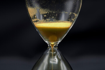 Detalle de un reloj de arena dorada, aislado con fondo negro	