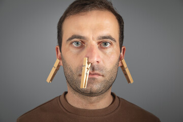 Clothespins on a caucasian male ear.