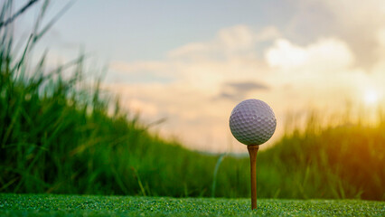 Golf ball on green grass in the evening golf course with sunshine background.