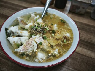 Description: A steaming bowl of snapper fish soup with tender fish chunks, vegetables, and a...