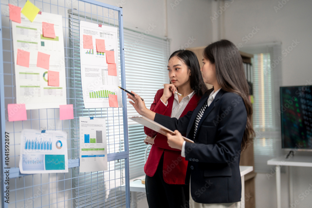 Wall mural two businesswomen discussing using data on board with sticky notes in office