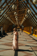 An Elegant Woman in a Flowing Dress Gracefully Stands in a Stunning Architectural Space