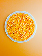 Orange masterbatch granules in a cup, isolated on orange background. Color pigment carrier polymer in the plastic industry.