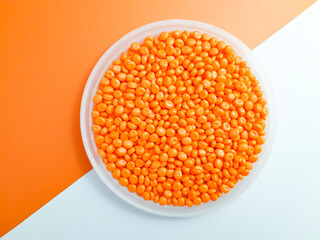 Orange masterbatch granules in a cup on a white and orange background.Color pigment carrier polymer...