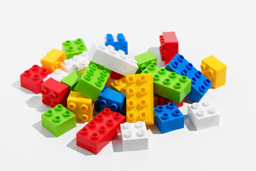 Obraz premium Mixed in a pile of colored plastic blocks or bricks toys for constructor on a white isolated background. The concept of children's educational games. Image for your design