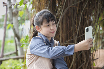 Happy smiling primary school child taking selfie photo with front camera on smartphone