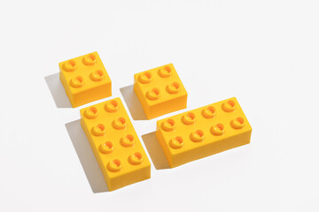 Close up of yellow plastic blocks bricks toy for building constructor on white isolated background in corner. The concept of children's educational games. Image for your design