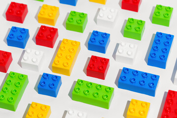 Angled view of many plastic colored pattern rainbow building toy brick blocks on white isolated...