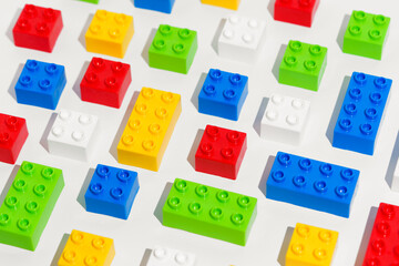 Angled view of many plastic colored pattern rainbow building toy brick blocks on white isolated...