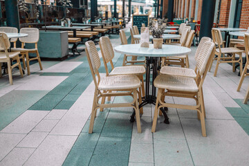 Wooden chairs with a green flowers in the middle of the table of an outdoor restarurant. High quality photo