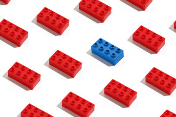 Pattern of many red rectangular blocks of bricks for construction and blue antagonist on white isolated background. The concept of confrontation and opposition, standing out from the crowd. 