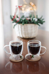 Wicker basket with Christmas gift set with two cups of coffee on the table. Strawberries and fir branches in a straw basket. New year sweet present. Christmas mood and cosy atmosphere at home