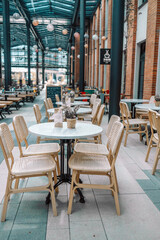 Wooden chairs with a green flowers in the middle of the table of an outdoor restarurant. High quality photo