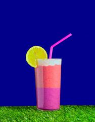 Mixed fruit smoothie garnished with a slice of lemon and a pink straw.